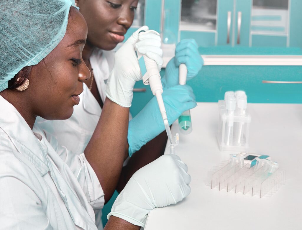 Two black female scientists using pipettes and test tubes.